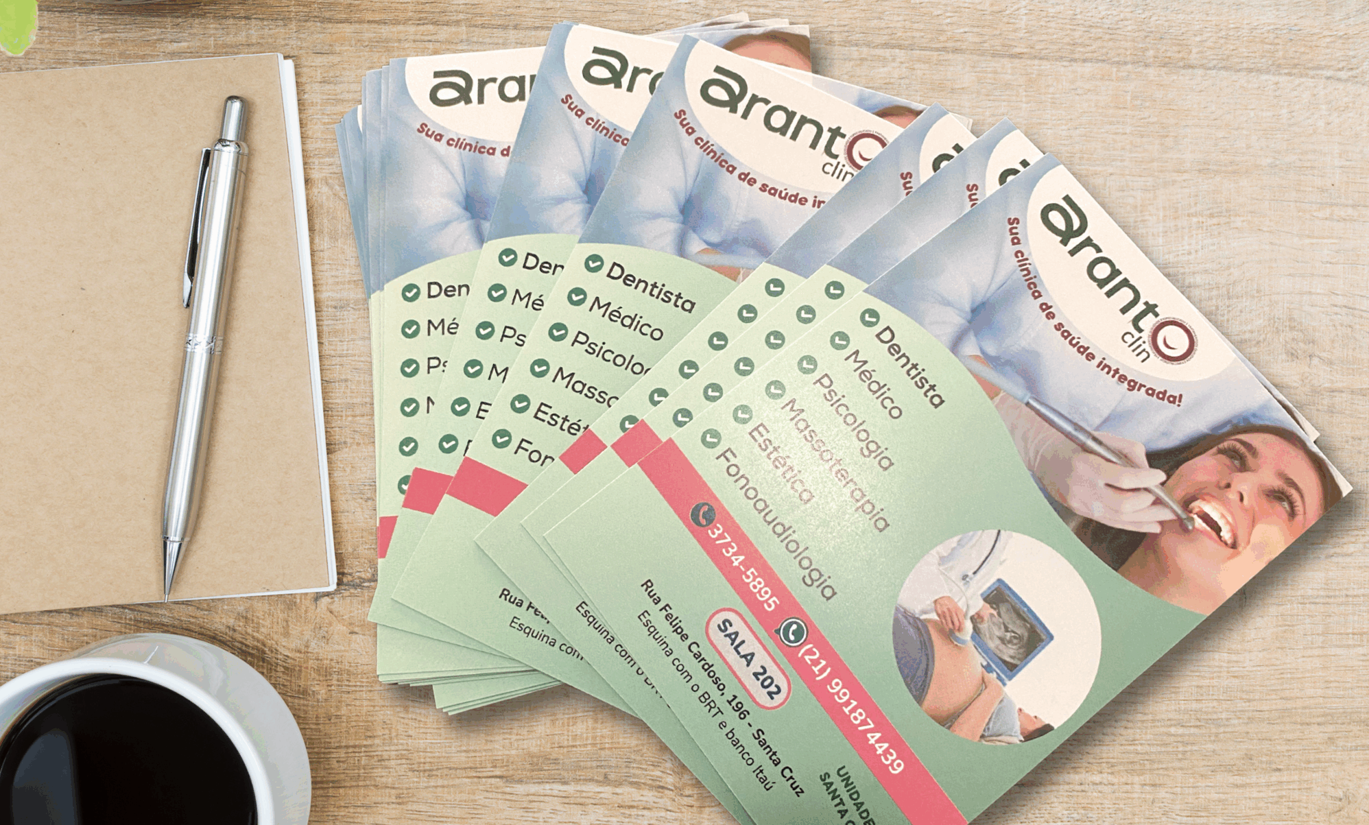 Imagem de panfletos coloridos impressos para clínica de saúde, dispostos sobre uma mesa com caderno, caneta e xícara de café. Exemplo de material gráfico promocional produzido por gráfica online no RJ, ideal para divulgação de serviços com flyers e panfletos personalizados em alta qualidade.