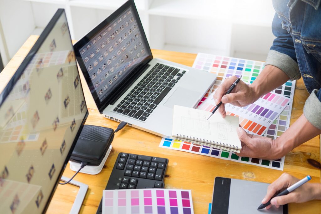 duas pessoas sentadas em uma mesa fazendo um serviço gráfico de cartão de visita, panfleto, banner, escolhendo cores para algum designer de impressão ou digital.